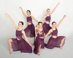 a group of young women in purple dresses posing for a photo with their arms outstretched