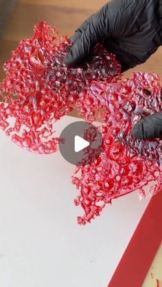 a person in black gloves is making something red