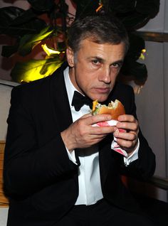 a man in a tuxedo eating a sandwich