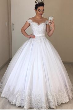 a woman in a white wedding dress taking a selfie while wearing a tiara