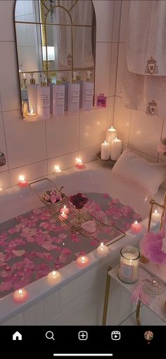 a bath tub filled with candles next to a mirror