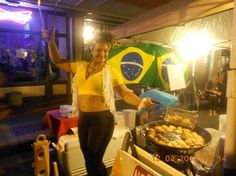 a woman standing in front of a table with food on it and a flag behind her