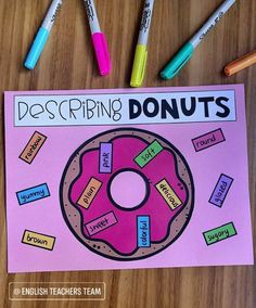 a pink doughnut with words describing donuts on it, surrounded by crayons