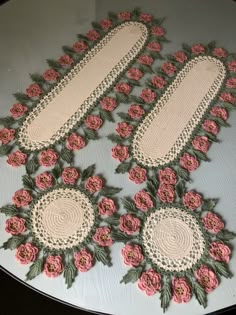 several pieces of crocheted doily with pink flowers on them sitting on a table