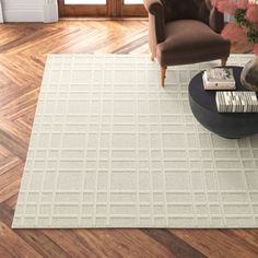 a living room with wooden floors and a large white rug on the floor next to a chair