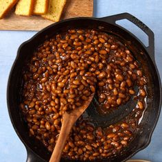 a skillet filled with baked beans next to slices of bread