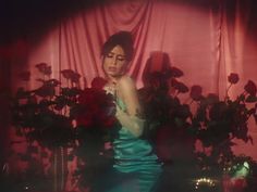 a woman in a blue dress standing next to flowers