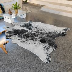 a black and white cowhide rug on the floor in a living room with modern furniture