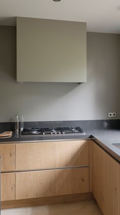 an empty kitchen with wooden cabinets and black counter tops is seen in this image from the side