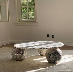 a marble coffee table sitting on top of a carpeted floor next to a window