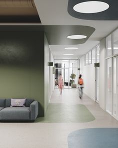 an office hallway with two people walking down the hall and one person in the background