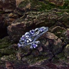 a silver ring with purple stones on rocks