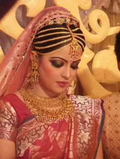 a woman in a red and gold bridal outfit looking down at her wedding day