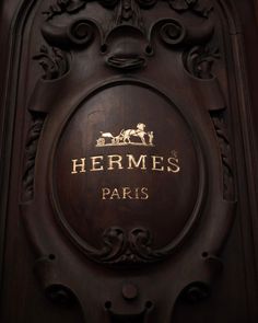 the sign for hermes paris is carved into an ornate wooden door