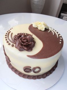 a white cake with chocolate frosting and a flower on the top is sitting on a plate