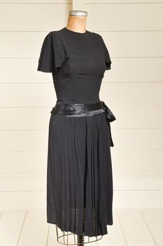 "1940s Accordion Sleeve Cocktail Dress Black Rayon w/ Satin Waist Deco Dress Darling 1940s era rayon dress. Pleated accordion sleeves with wide satin belt bow tie. Hidden side metal zipper to close the back neck & side. (Zips up just fine, dress was small on my dress form) In good vintage condition, showing normal signs of wear. Measurements shoulders: free bust: 32\" waist: 25\" hips: 52\" length: 46.5\"" Vintage Solid Color Formal Dress, Retro Fitted Rayon Dresses, Vintage Fitted Dress With Pleated Waist, Vintage Pleated Evening Dress, Vintage Rayon Dresses For Daywear, Fitted Vintage Rayon Dress, Vintage Evening Dress With Pleated Waist, Formal Vintage Pleated Dress, Formal Pleated Vintage Dress