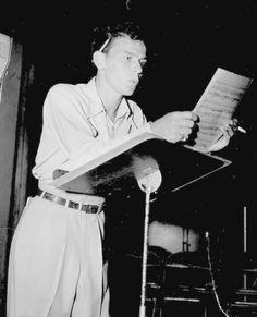 a man standing at a microphone holding a piece of paper