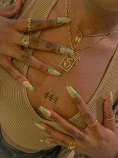 a woman with green and white nail polish holding her hands in front of her chest