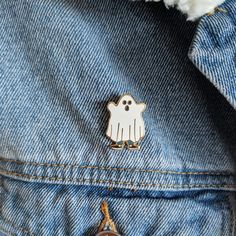 a white ghost pin sitting on top of a blue jean jacket