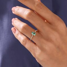 a woman's hand wearing a ring with a green stone on it and a diamond in the middle