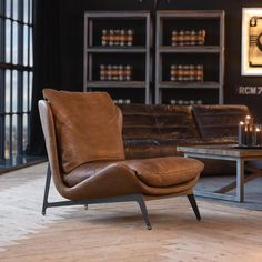 a brown leather chair sitting on top of a wooden floor next to a coffee table