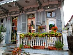 an old house with flowers and potted plants on the front porch