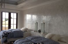 two beds in a room with white walls and windows