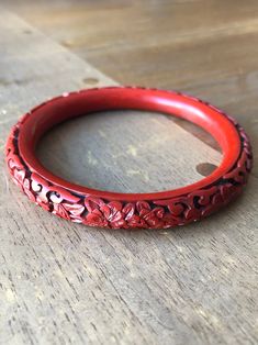 Unique Chinese ethnic style vintage Carved Floral Pattern Cinnabar Lacquer Bangle from the 70s. Beijing carved cinnabar lacquer ware is a traditional Chinese arts and crafts. By carving landscapes, bird-flowers and human figures on the moulded body of an article which is coated with relatively thick layers of lacquer. This arts crafting has been started far back during Han (漢) Dynasty (B.C. 206 - 220 A.D.). The processes involved in carved cinnabar lacquer ware are very complicated. In general, Handmade Red Bangle, Vintage Red Bracelet For Gifts, Vintage Red Bracelet As A Gift, Red Carved Vintage Jewelry, Carved Red Vintage Jewelry, Vintage Carved Bracelets For Ceremonial Occasions, Vintage Red Round Bangle, Vintage Handmade Red Bangle, Elegant Red Ceremonial Bracelets