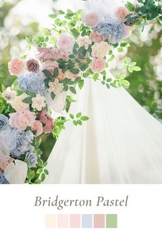 the wedding arch is decorated with flowers and greenery for an outdoor ceremony in pastel tones