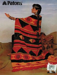 a woman sitting on top of a couch covered in a blanket and holding a basket