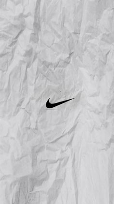 a black and white photo of a nike logo on crumpled paper with watermarked