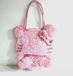 a pink hello kitty handbag hanging on a wall next to a stuffed animal toy