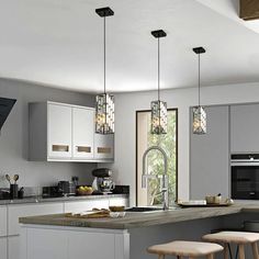 a kitchen with an island and stools in front of the counter top, along with two lights hanging from the ceiling