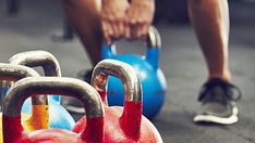 two kettles with handles are on the ground in front of a man doing push ups