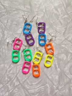 six pairs of neon colored plastic earrings on a white surface with the word good written in large letters