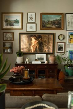 a living room filled with lots of pictures on the wall above a wooden coffee table