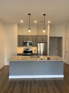 an empty kitchen with stainless steel appliances and wood flooring in it's new home