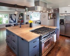 a kitchen with stainless steel appliances and wooden counter tops, along with an island in the middle