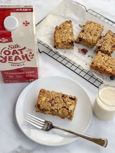 a white plate topped with oatmeal bars next to a carton of milk