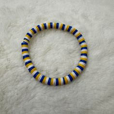 Handcrafted bracelet featuring blue, yellow, and white heishi clay beads. This stretchy bracelet is ideal for displaying your school spirit from high school or college. It is also a wonderful way to show support for your favorite college teams like the Notre Dame Fighting Irish and the Michigan Wolverines. Size of bracelet in photo: 7 1/2 inches Clay Bead Bracelet Ideas, Clay Bead Bracelet, Yellow Bracelet, Blue Clay, Clay Bracelet, Clay Bead, Handcrafted Bracelets, Bracelet Ideas, Michigan Wolverines