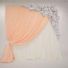 an orange and white backdrop with flowers on the top, along with sheer drapes