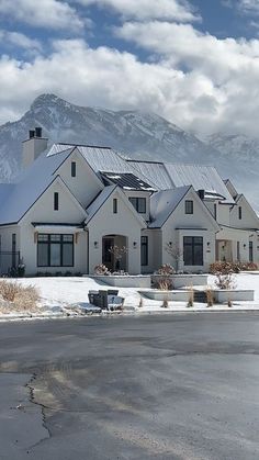 a large white house with snow on the ground and mountains in the backround