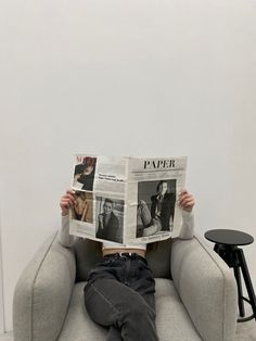 a person sitting on a couch reading a paper