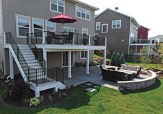 a patio with an umbrella and couches in front of a house on the lawn