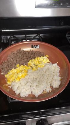 an orange plate with rice, eggs and meat on top of it next to an oven