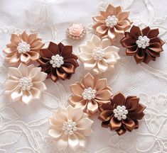 four different types of flowers on a white lace tablecloth with pearls and beads in the center