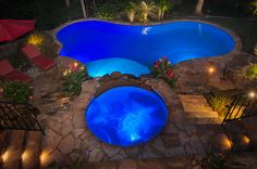 an aerial view of a pool at night with lights on the side and steps leading up to it