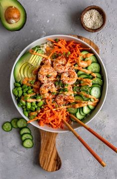 shrimp, carrots and cucumbers in a bowl with chopsticks on the side