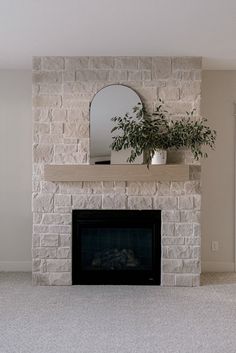 a living room with a fireplace, mirror and potted plant on the mantel