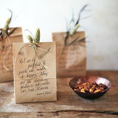 three brown bags with some nuts in them on a table next to a wooden bowl